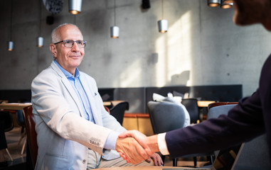 Senior businessman shaking hands during meeting in cafe
