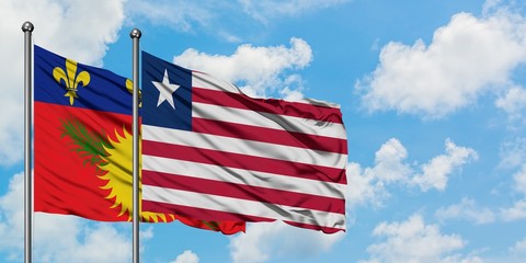 Guadeloupe and Liberia flag waving in the wind against white cloudy blue sky together. Diplomacy concept, international relations.