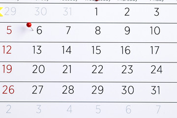 Planning calendar with red pin on a blue wooden background. Important date. Place for text. Planning concept.