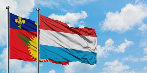 Guadeloupe and Luxembourg flag waving in the wind against white cloudy blue sky together. Diplomacy concept, international relations.