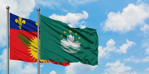 Guadeloupe and Macao flag waving in the wind against white cloudy blue sky together. Diplomacy concept, international relations.