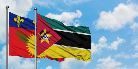 Guadeloupe and Mozambique flag waving in the wind against white cloudy blue sky together. Diplomacy concept, international relations.