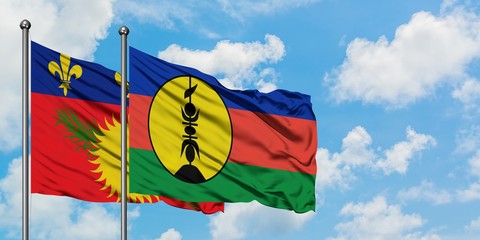 Guadeloupe and New Caledonia flag waving in the wind against white cloudy blue sky together. Diplomacy concept, international relations.