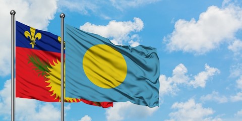 Guadeloupe and Palau flag waving in the wind against white cloudy blue sky together. Diplomacy concept, international relations.