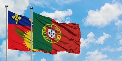 Guadeloupe and Portugal flag waving in the wind against white cloudy blue sky together. Diplomacy concept, international relations.