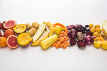 top view of red onions, beetroots, carrots, potatoes, apricots, melon, bananas, zucchini pumpkin and grapefruit on white background