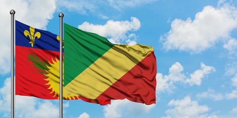 Guadeloupe and Republic Of The Congo flag waving in the wind against white cloudy blue sky together. Diplomacy concept, international relations.