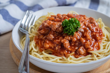 Spaghetti bolognese in white bowl.