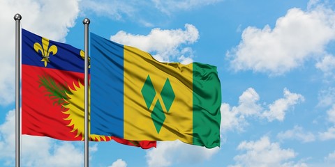 Guadeloupe and Saint Vincent And The Grenadines flag waving in the wind against white cloudy blue sky together. Diplomacy concept, international relations.