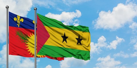 Guadeloupe and Sao Tome And Principe flag waving in the wind against white cloudy blue sky together. Diplomacy concept, international relations.
