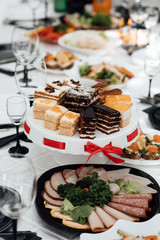 Serves dinner on a festive table. Food, Salads, Meat, Fish Meals. Festive table at wedding banquet. Decor. Details. Served tables at the Banquet. Drinks, snacks, delicacies. A gala event or wedding.