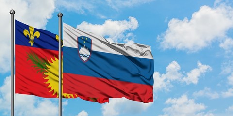 Guadeloupe and Slovenia flag waving in the wind against white cloudy blue sky together. Diplomacy concept, international relations.