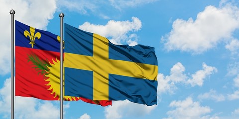 Guadeloupe and Sweden flag waving in the wind against white cloudy blue sky together. Diplomacy concept, international relations.