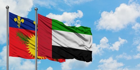 Guadeloupe and United Arab Emirates flag waving in the wind against white cloudy blue sky together. Diplomacy concept, international relations.