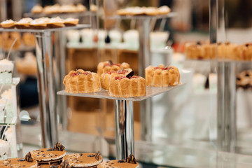 Beautiful dessert table in restaurant. Wedding decoration with pastel colored cupcakes. Elegant and luxurious event arrangement with macaroons.