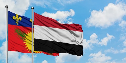 Guadeloupe and Yemen flag waving in the wind against white cloudy blue sky together. Diplomacy concept, international relations.