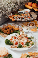 Decorated catering banquet table with different sushi rolls and sushi plate assortment on a party. Food for party. Delicious cuisine menu in tasty food restaurant. Table for banquets, weddings, partie
