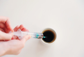 Hand picks espresso into a medical syringe. Caffeine addiction symbol. White background