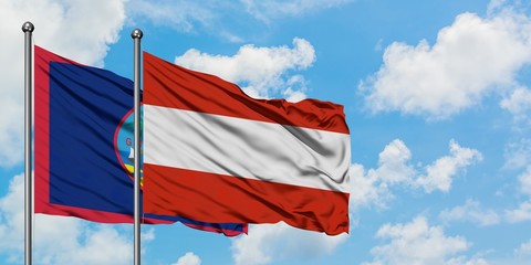 Guam and Austria flag waving in the wind against white cloudy blue sky together. Diplomacy concept, international relations.