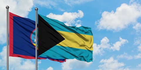 Guam and Bahamas flag waving in the wind against white cloudy blue sky together. Diplomacy concept, international relations.