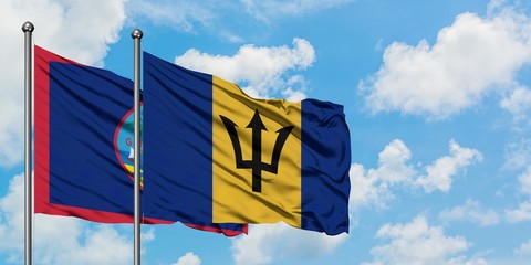 Guam and Barbados flag waving in the wind against white cloudy blue sky together. Diplomacy concept, international relations.