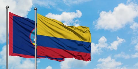 Guam and Colombia flag waving in the wind against white cloudy blue sky together. Diplomacy concept, international relations.