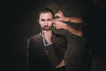 Successful confident male in classic suit is visiting a barbershop for beard trimming.