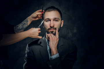 Confident elegant businessman receive a beard care from female with nice manicure.