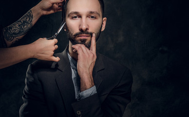 Confident elegant businessman receive a beard care from female with nice manicure.