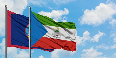 Guam and Equatorial Guinea flag waving in the wind against white cloudy blue sky together. Diplomacy concept, international relations.