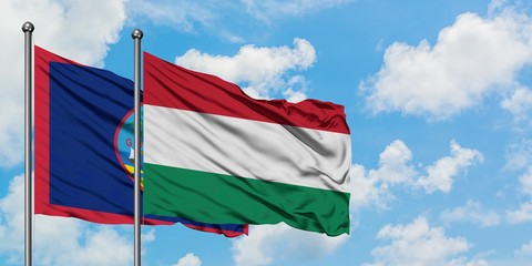 Guam and Hungary flag waving in the wind against white cloudy blue sky together. Diplomacy concept, international relations.