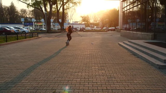 A roller-skating girl rides with her back to the camera on a city street.