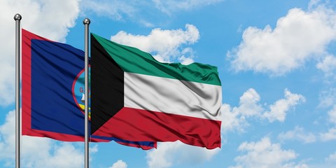 Guam and Kuwait flag waving in the wind against white cloudy blue sky together. Diplomacy concept, international relations.