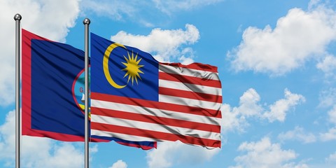 Guam and Malaysia flag waving in the wind against white cloudy blue sky together. Diplomacy concept, international relations.