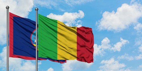 Guam and Mali flag waving in the wind against white cloudy blue sky together. Diplomacy concept, international relations.