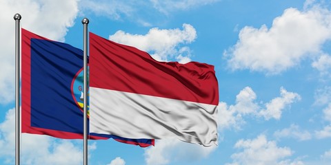 Guam and Monaco flag waving in the wind against white cloudy blue sky together. Diplomacy concept, international relations.