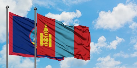 Guam and Mongolia flag waving in the wind against white cloudy blue sky together. Diplomacy concept, international relations.