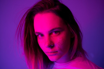 Young girl portrait in neon pink and violet lights with glitter freckles on face. Clubber, night life concept. Copy space.