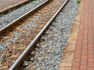 Railroad tracks at train station and sidewalks beside the railway, Transportation and holiday concept.