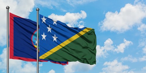Guam and Solomon Islands flag waving in the wind against white cloudy blue sky together. Diplomacy concept, international relations.