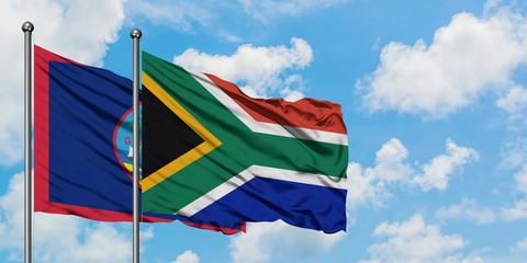 Guam and South Africa flag waving in the wind against white cloudy blue sky together. Diplomacy concept, international relations.