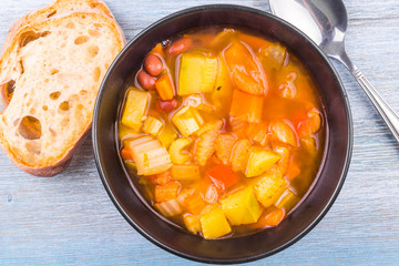 A bowl of traditional vegetarian Italian vegetable soup with beans, celery, tomatoes, carrots,...