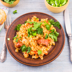 Traditional New Orleans jumbalaya with rice, chicken and sausages, on a clay plate, sprinkled with chopped parsley.