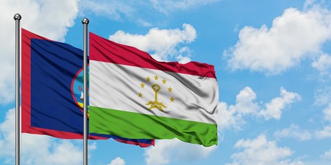 Guam and Tajikistan flag waving in the wind against white cloudy blue sky together. Diplomacy concept, international relations.
