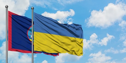 Guam and Ukraine flag waving in the wind against white cloudy blue sky together. Diplomacy concept, international relations.