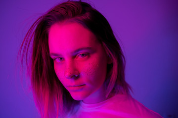Young girl portrait in neon pink and violet lights with glitter freckles on face. Clubber, night life concept. Copy space.