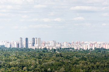 Fototapeta premium Urban scene with trees in city park, skyscrapers and buildings