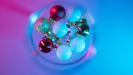 empty glass of wine with christmas tree ball decorations in pink and blue neon gradient light