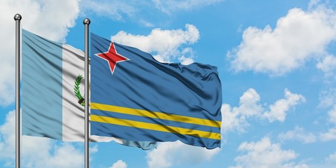 Guatemala and Aruba flag waving in the wind against white cloudy blue sky together. Diplomacy concept, international relations.