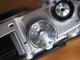 Dial mode and shutter button on silver mirrorless camera.